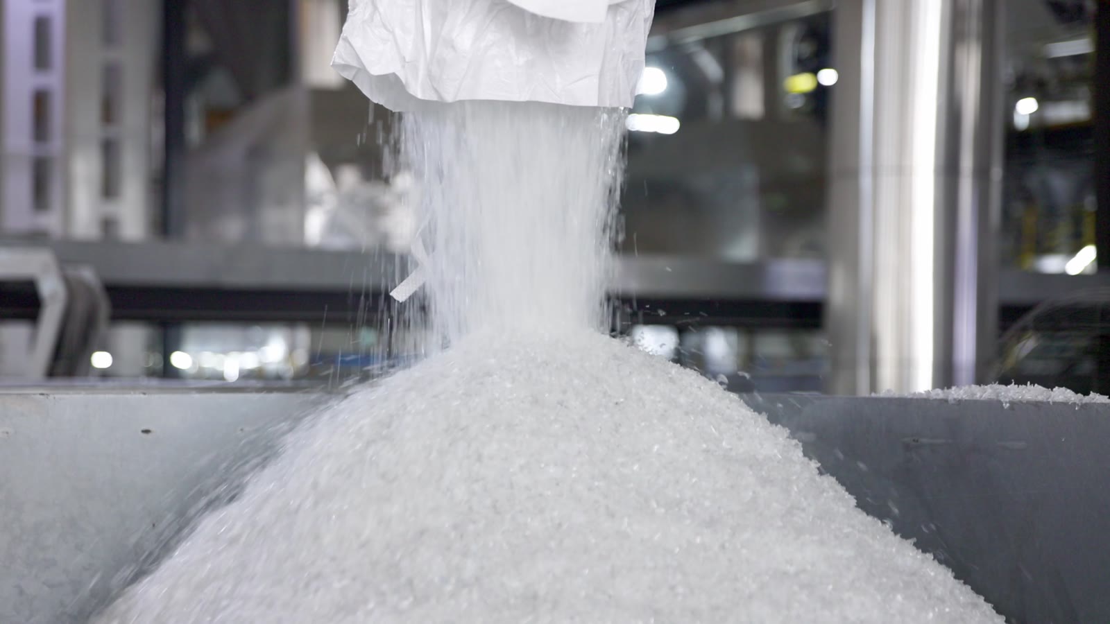 Plastic granules entering industrial processing equipment